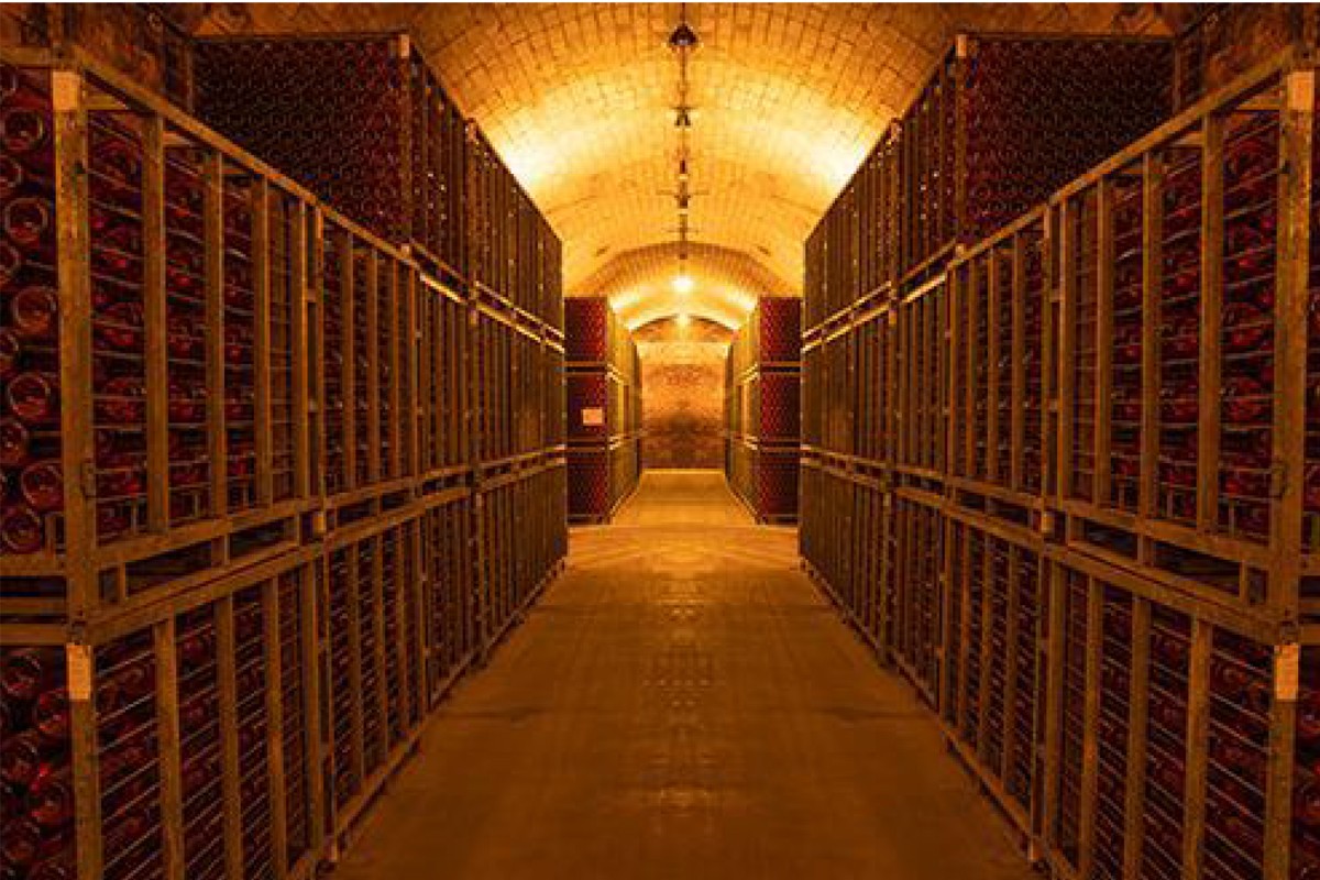 Interior de la bodega Naveran, con botellas en crianza bajo una bóveda de ladrillo